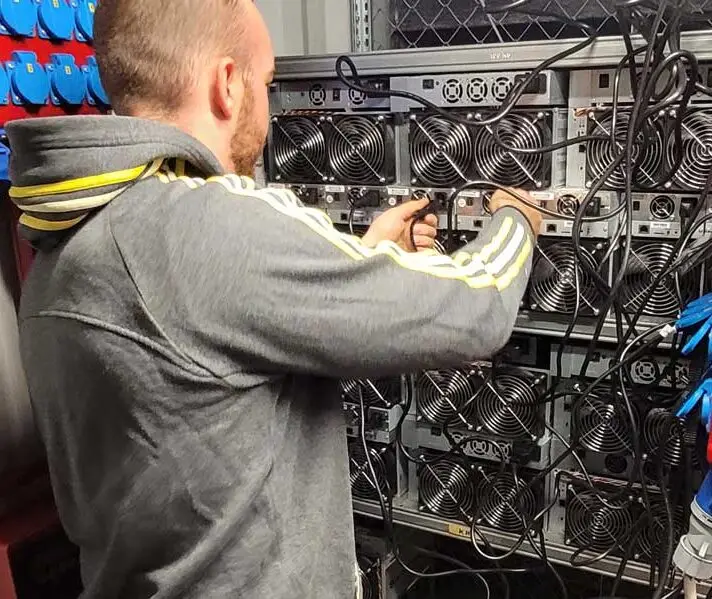 Hamus hosting staff operating the power switch on a Bitcoin miner, symbolising the immediate start of miner hosting services at Hamus Hosting.