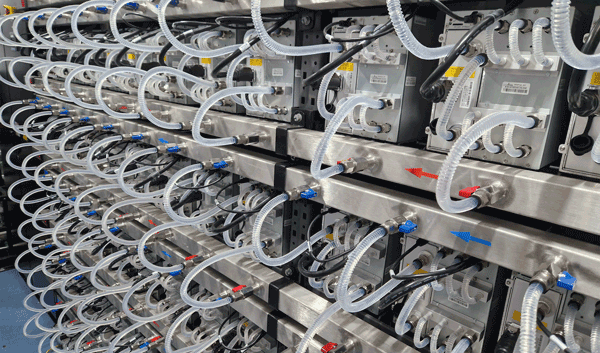 A row of Bitmain hydro miners operating inside an HK3 container, with visible cooling infrastructure and cables neatly organized.