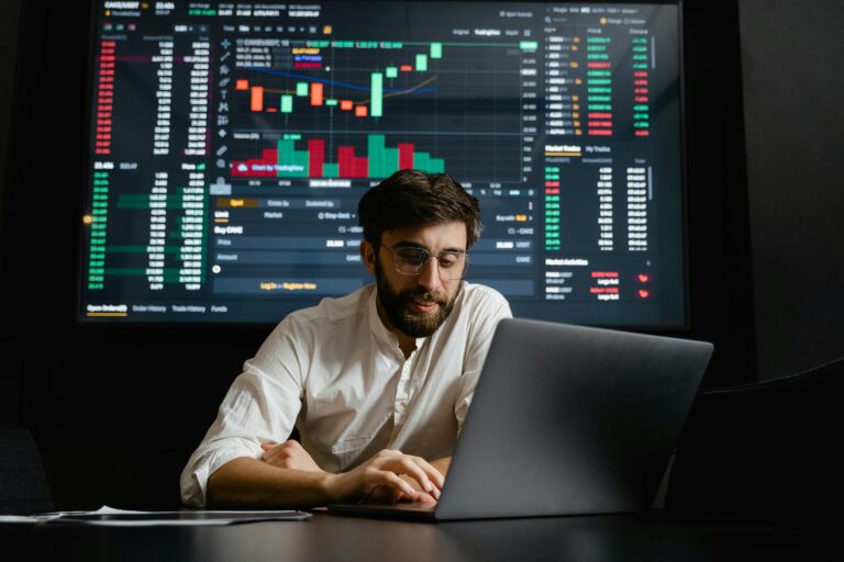 Man smiling sitting infront of his laptop working on mining bitcoin